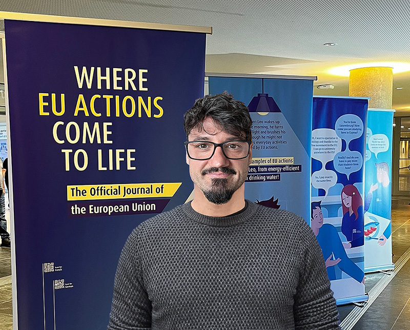 George Alex Stelea standing in front of EU promotional banners highlighting the Official Journal of the European Union at a Publications Office outreach event, showcasing EU communication and transparency initiatives.